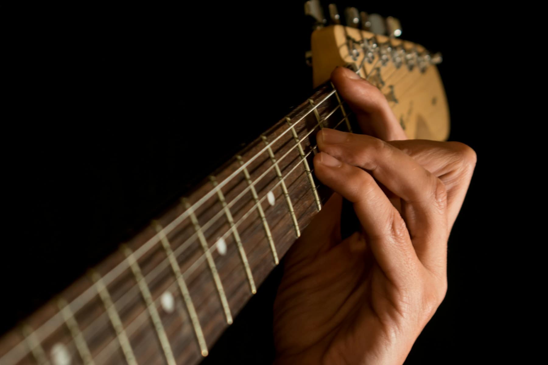 Tangan membentuk chord pada leher gitar