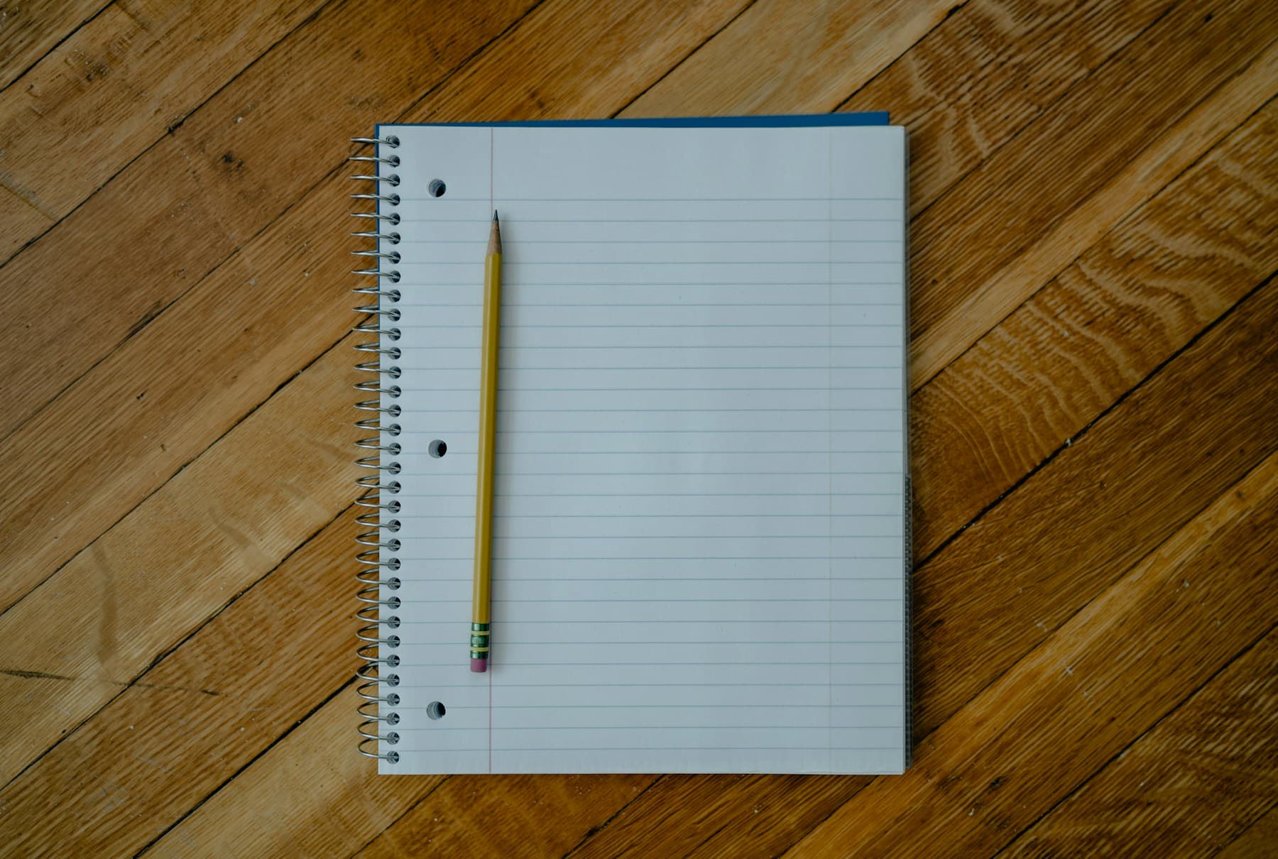 Buku catatan bergaris dan pensil di atas meja