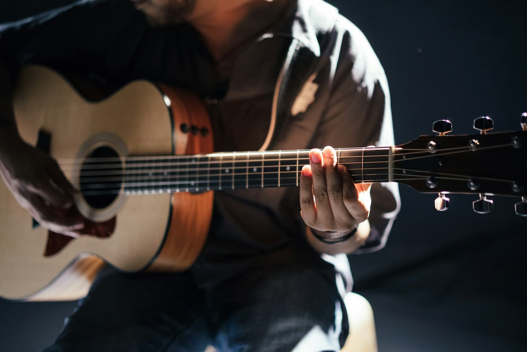 Seorang pemain memegang gitar akustik